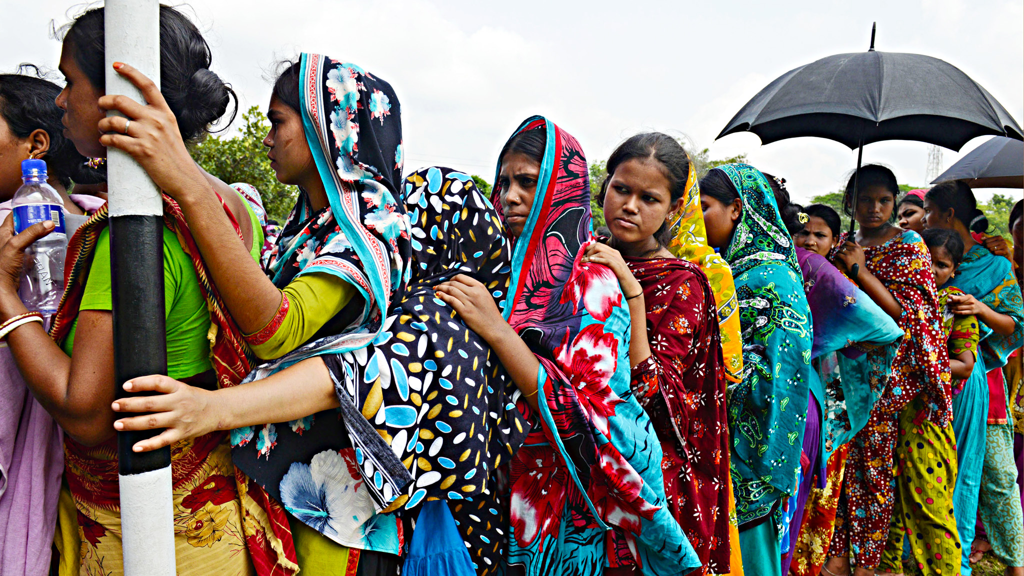 Garment workers employed at Rana Plaza stand in a queue to receive wages in Dhaka